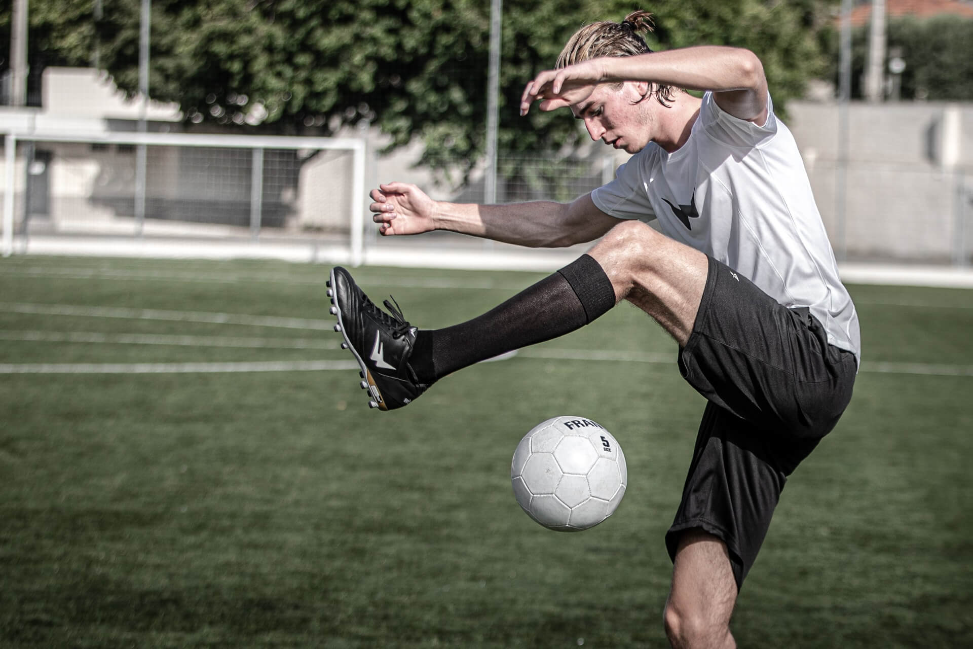 Joueur de football homme faisant des jongles avec des crampons de football rugby Wizwedge noires