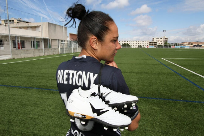 Sandrine Bretigny, sur un terrain tenant des chaussures de football Wizwedge blanches
